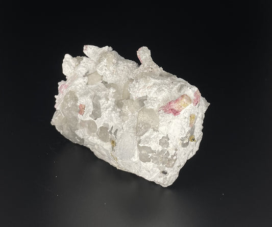 A close-up image of a mineral specimen featuring creamy Orthoclase crystals intergrown with clear quartz and dark tourmaline, showcasing a striking blend of textures and colors.
