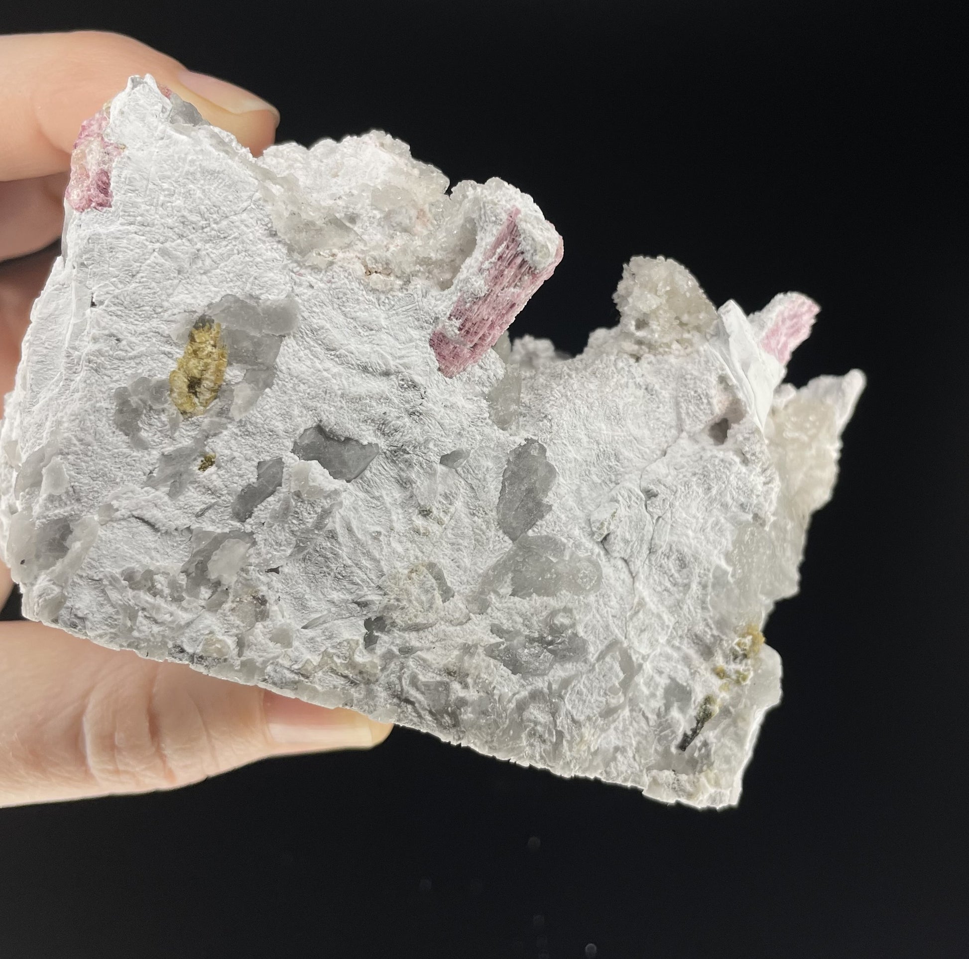 A close-up image of a mineral specimen featuring creamy Orthoclase crystals intergrown with clear quartz and dark tourmaline, showcasing a striking blend of textures and colors.