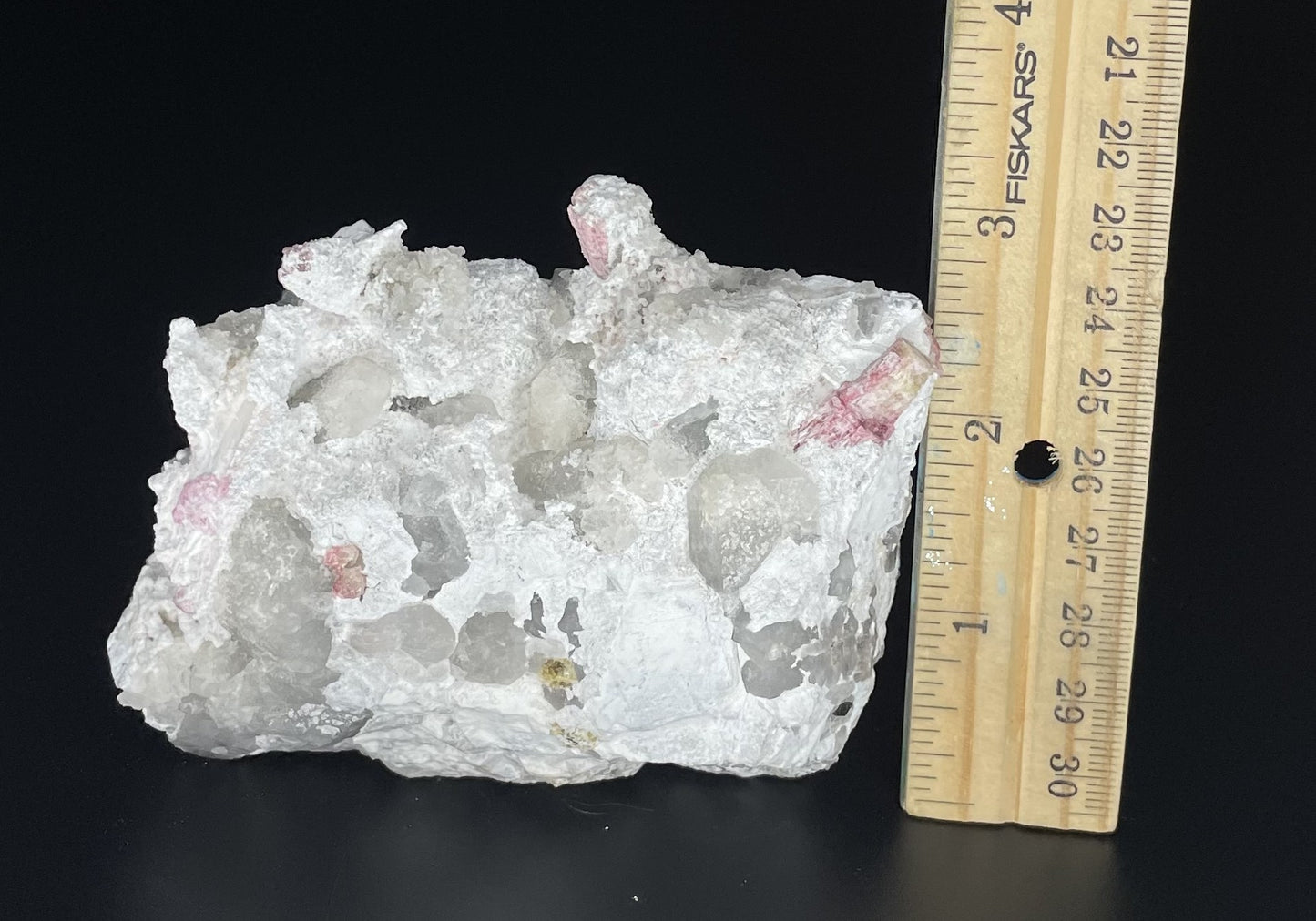 A close-up image of a mineral specimen featuring creamy Orthoclase crystals intergrown with clear quartz and dark tourmaline, showcasing a striking blend of textures and colors.