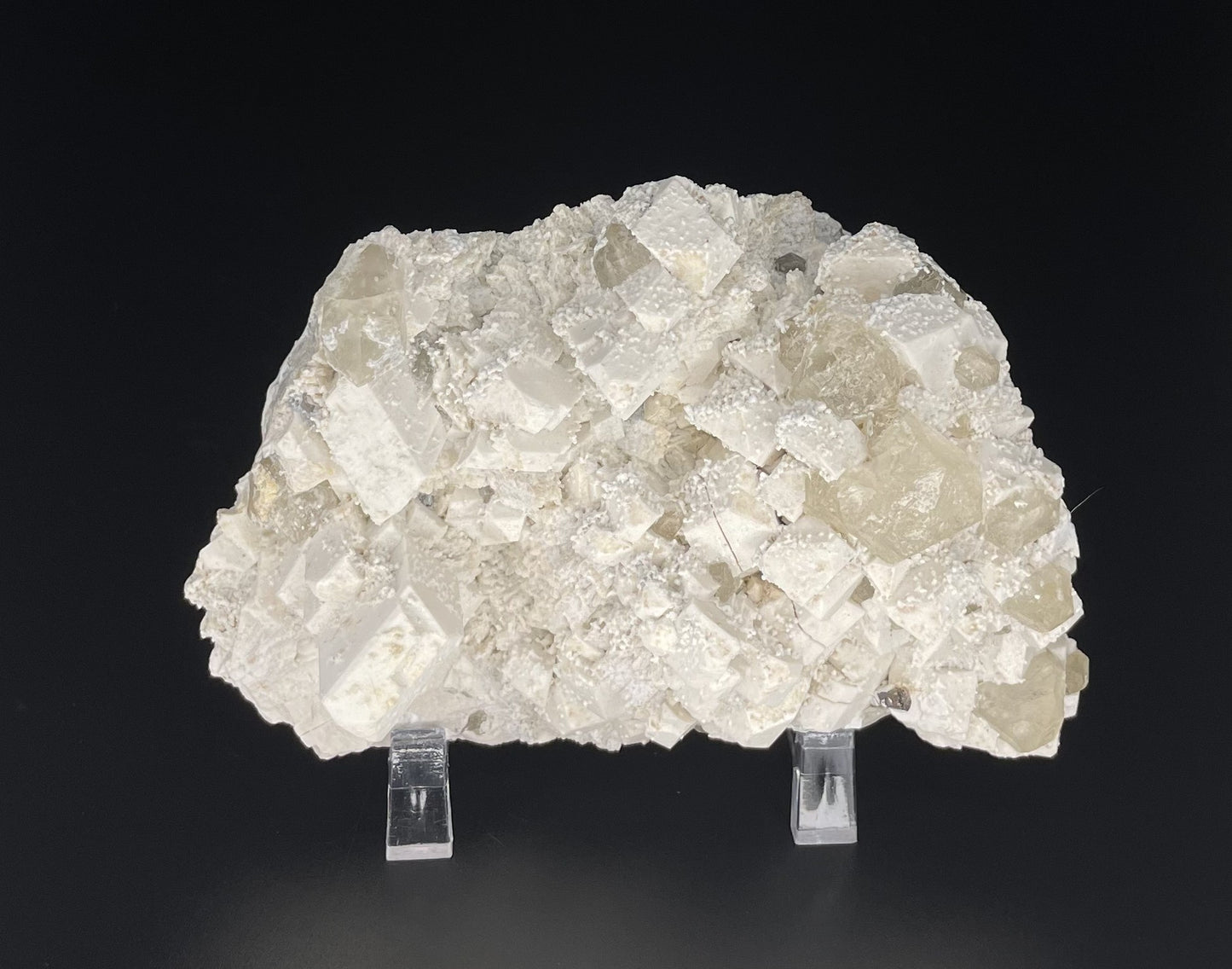 A close-up image of a mineral specimen featuring creamy Orthoclase crystals intergrown with clear quartz and dark tourmaline, showcasing a striking blend of textures and colors.