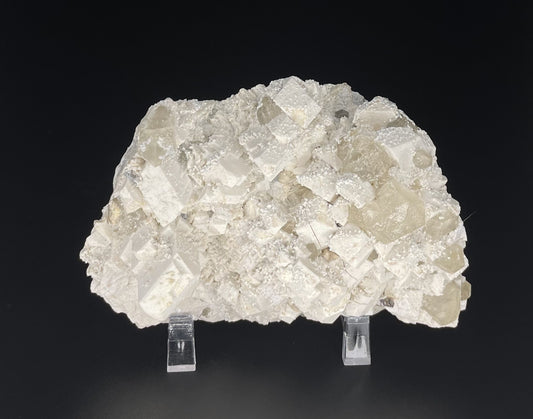 A close-up image of a mineral specimen featuring creamy Orthoclase crystals intergrown with clear quartz and dark tourmaline, showcasing a striking blend of textures and colors.
