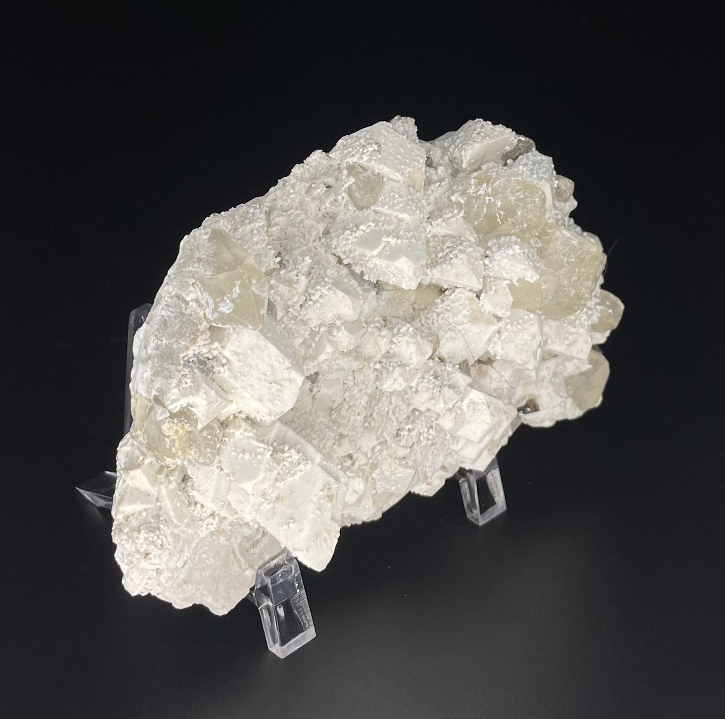 A close-up image of a mineral specimen featuring creamy Orthoclase crystals intergrown with clear quartz and dark tourmaline, showcasing a striking blend of textures and colors.