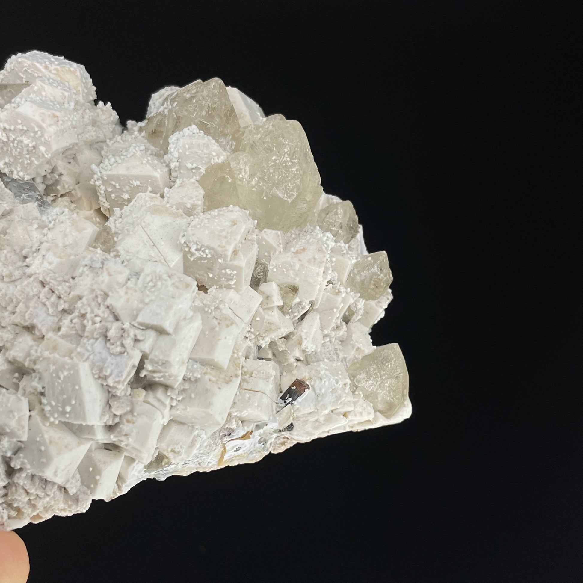A close-up image of a mineral specimen featuring creamy Orthoclase crystals intergrown with clear quartz and dark tourmaline, showcasing a striking blend of textures and colors.