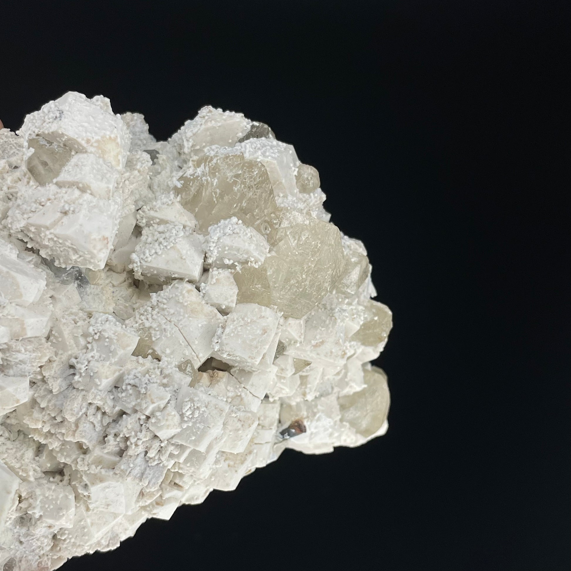 A close-up image of a mineral specimen featuring creamy Orthoclase crystals intergrown with clear quartz and dark tourmaline, showcasing a striking blend of textures and colors.