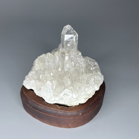 A natural Clear Quartz cluster with multiple crystal points, reflecting light beautifully against a neutral background.