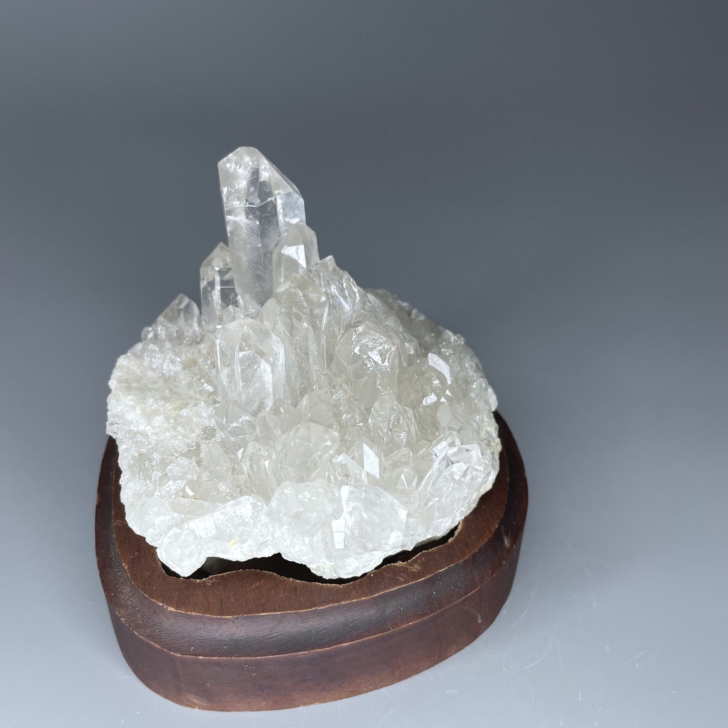 A natural Clear Quartz cluster with multiple crystal points, reflecting light beautifully against a neutral background.