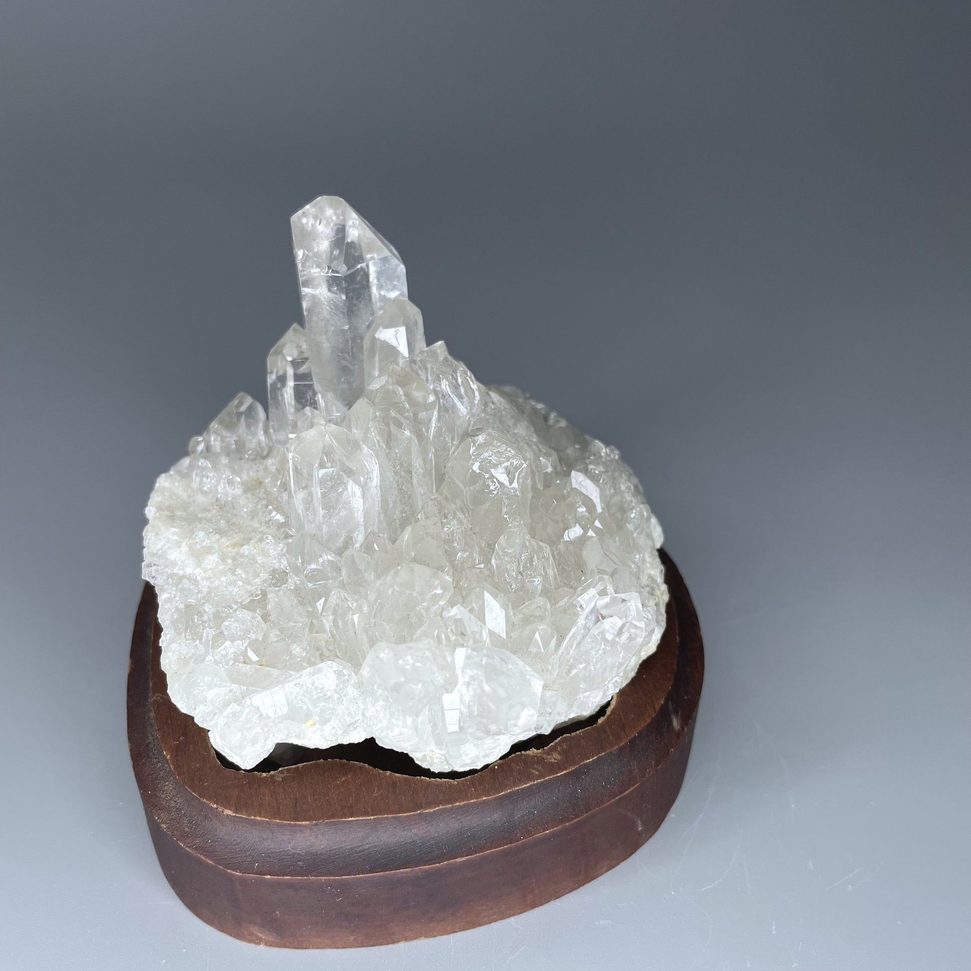 A natural Clear Quartz cluster with multiple crystal points, reflecting light beautifully against a neutral background.
