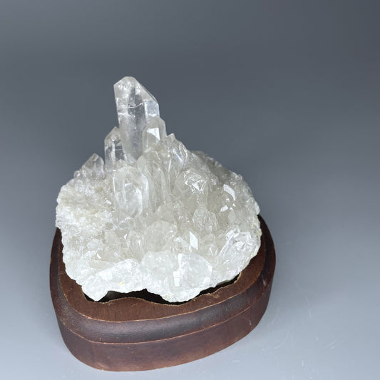 A natural Clear Quartz cluster with multiple crystal points, reflecting light beautifully against a neutral background.