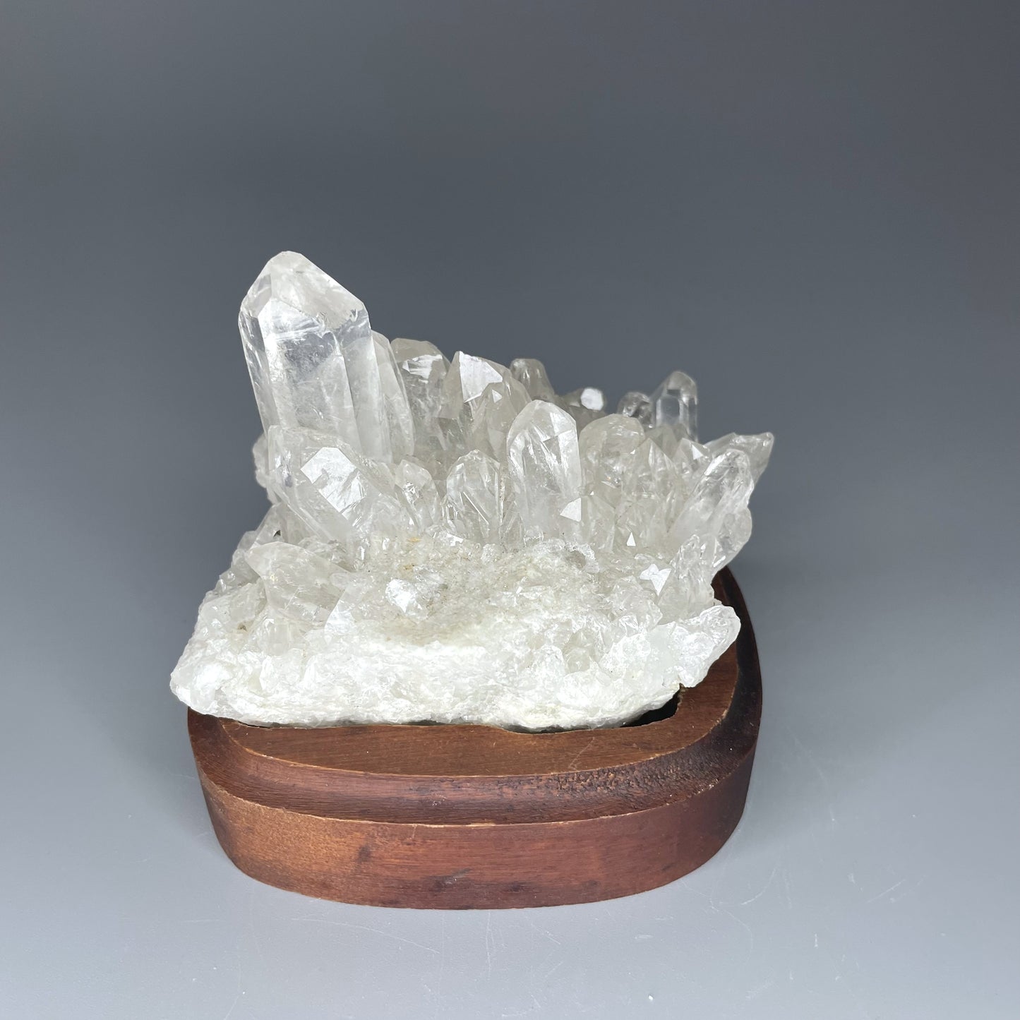 A natural Clear Quartz cluster with multiple crystal points, reflecting light beautifully against a neutral background.