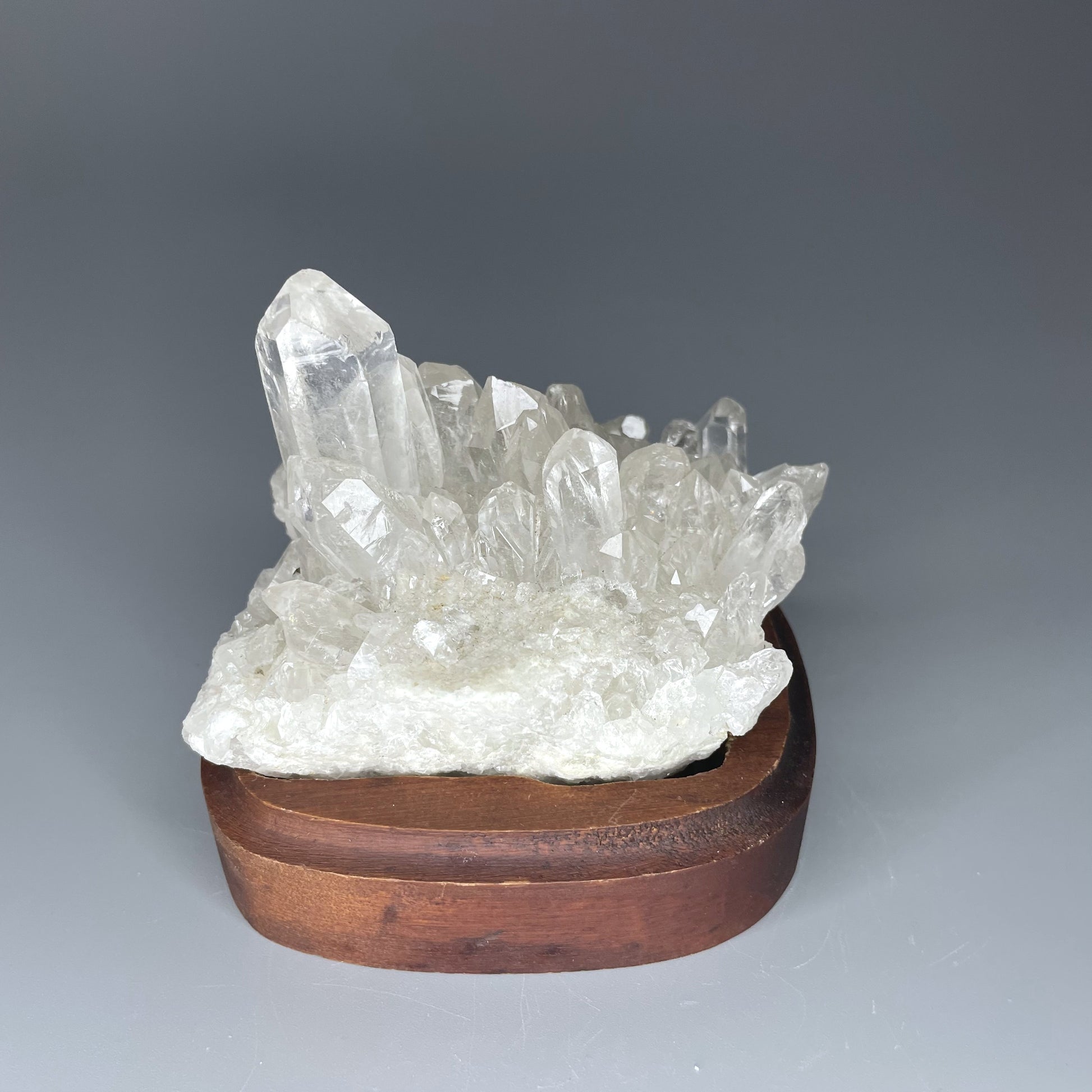 A natural Clear Quartz cluster with multiple crystal points, reflecting light beautifully against a neutral background.