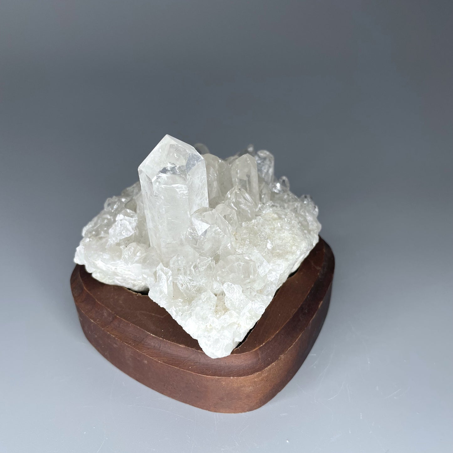 A natural Clear Quartz cluster with multiple crystal points, reflecting light beautifully against a neutral background.