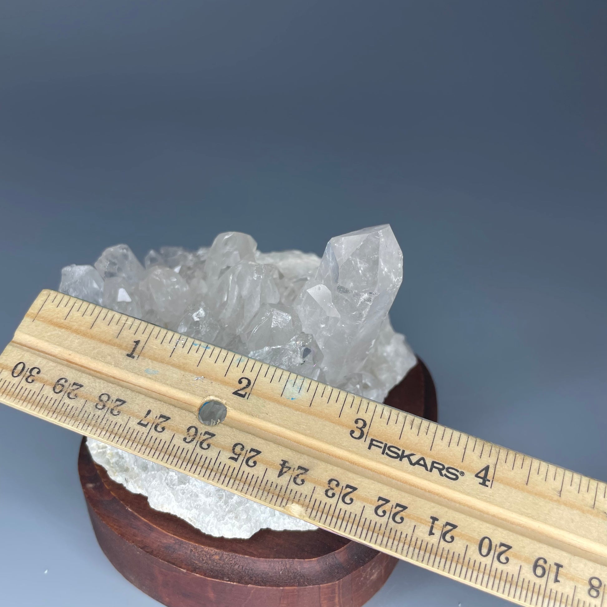 A natural Clear Quartz cluster with multiple crystal points, reflecting light beautifully against a neutral background.