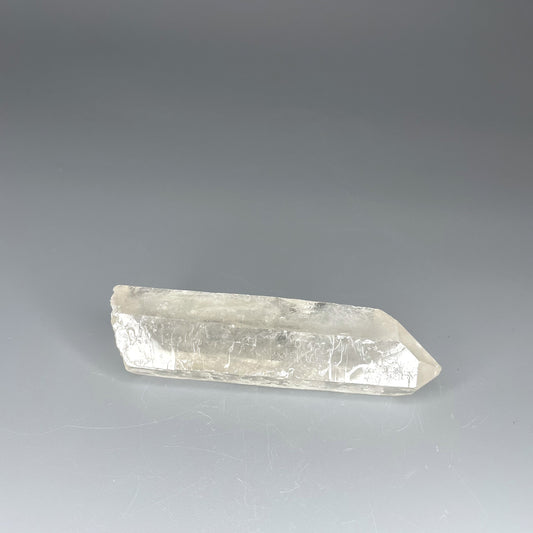A 4-inch polished Clear Quartz point with a smooth finish, standing upright against a neutral background.