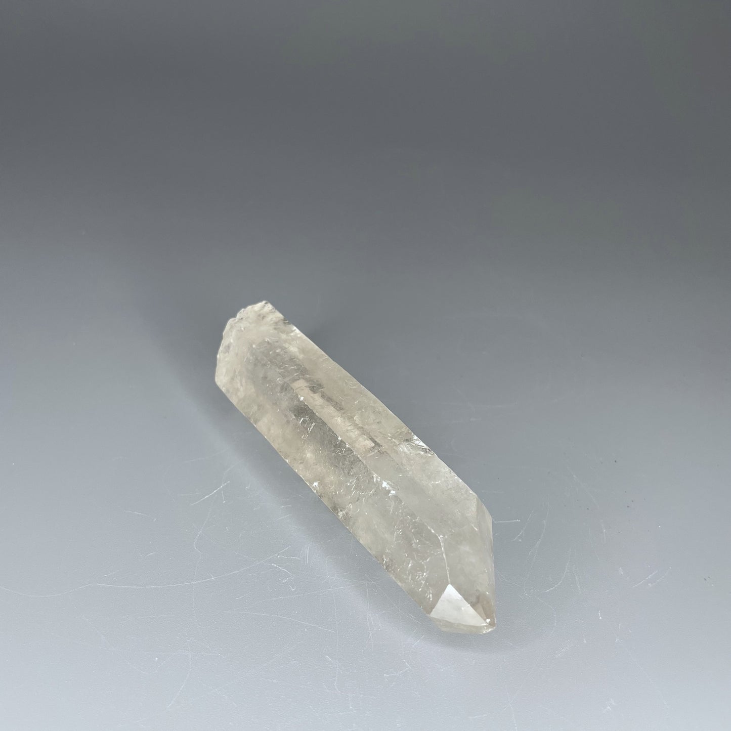 A 4-inch polished Clear Quartz point with a smooth finish, standing upright against a neutral background.