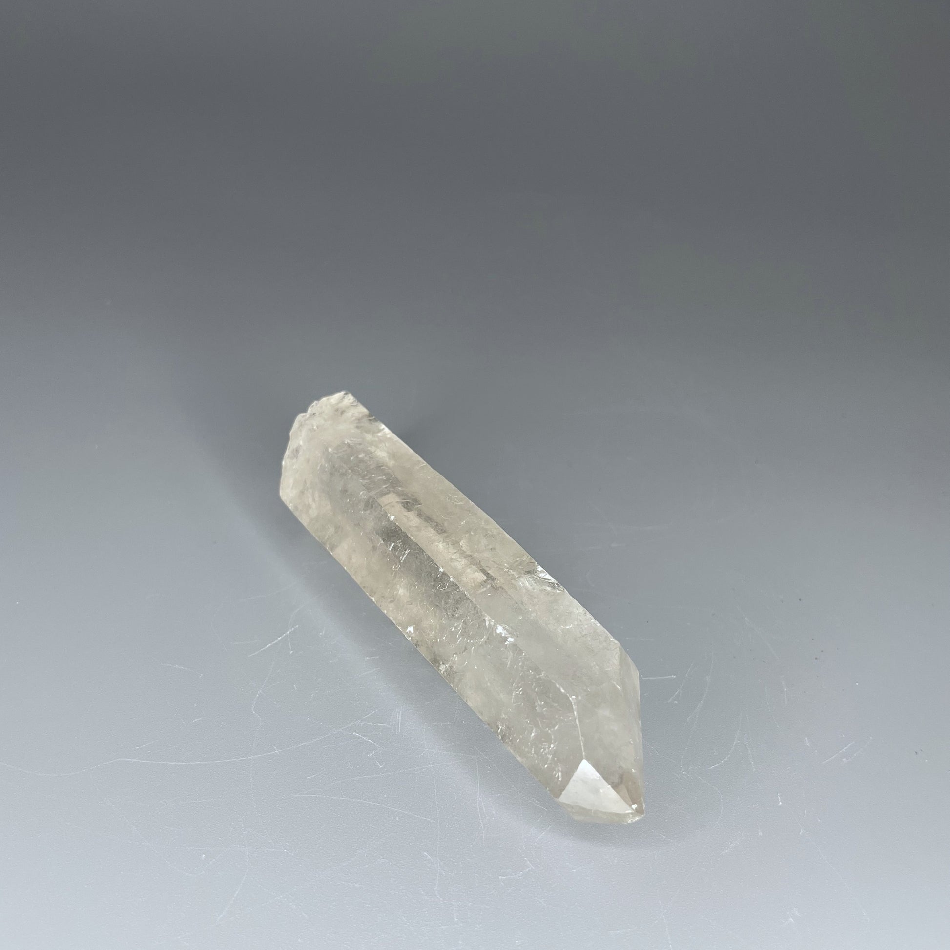 A 4-inch polished Clear Quartz point with a smooth finish, standing upright against a neutral background.