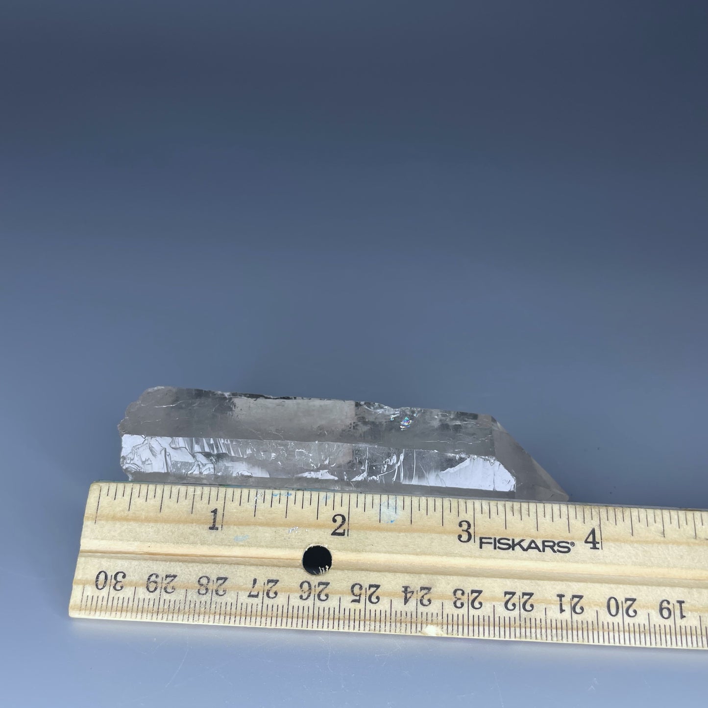 A 4-inch polished Clear Quartz point with a smooth finish, standing upright against a neutral background.