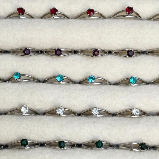 An image of a collection of birthstone rings with synthetic gems and adjustable bands. The rings come in various colors and styles, each featuring a vibrant synthetic gemstone representing a specific birth month. The bands are designed to be adjustable, allowing for a comfortable and customizable fit for different finger sizes. The rings are displayed against a neutral background, highlighting their beauty and versatility.