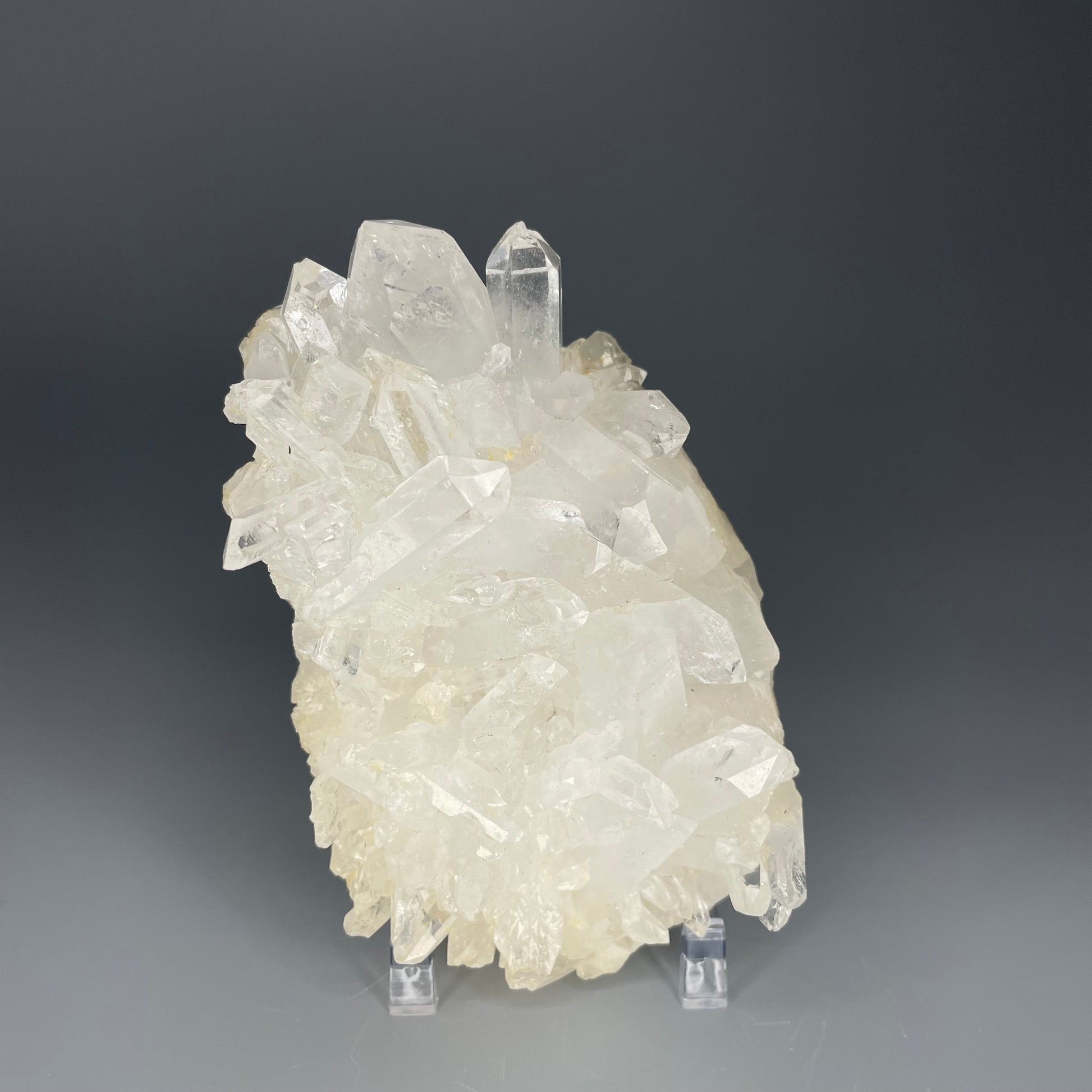 A natural Clear Quartz cluster with multiple crystal points, reflecting light beautifully against a neutral background.