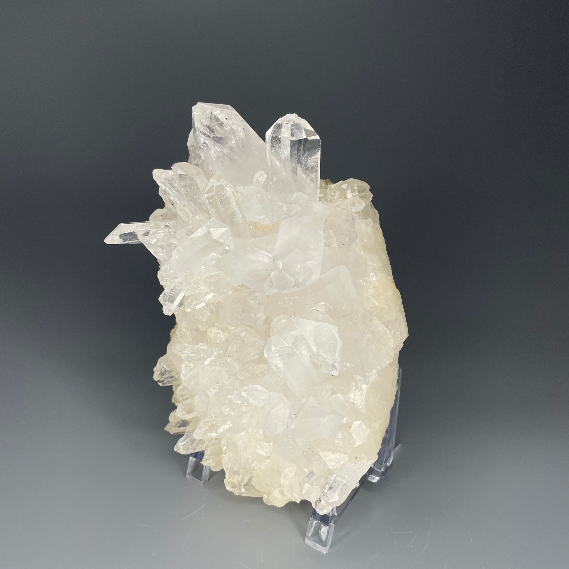 A natural Clear Quartz cluster with multiple crystal points, reflecting light beautifully against a neutral background.
