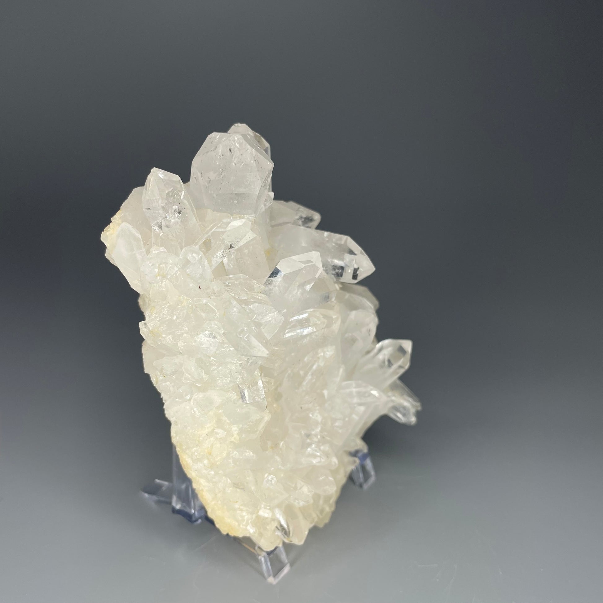 A natural Clear Quartz cluster with multiple crystal points, reflecting light beautifully against a neutral background.