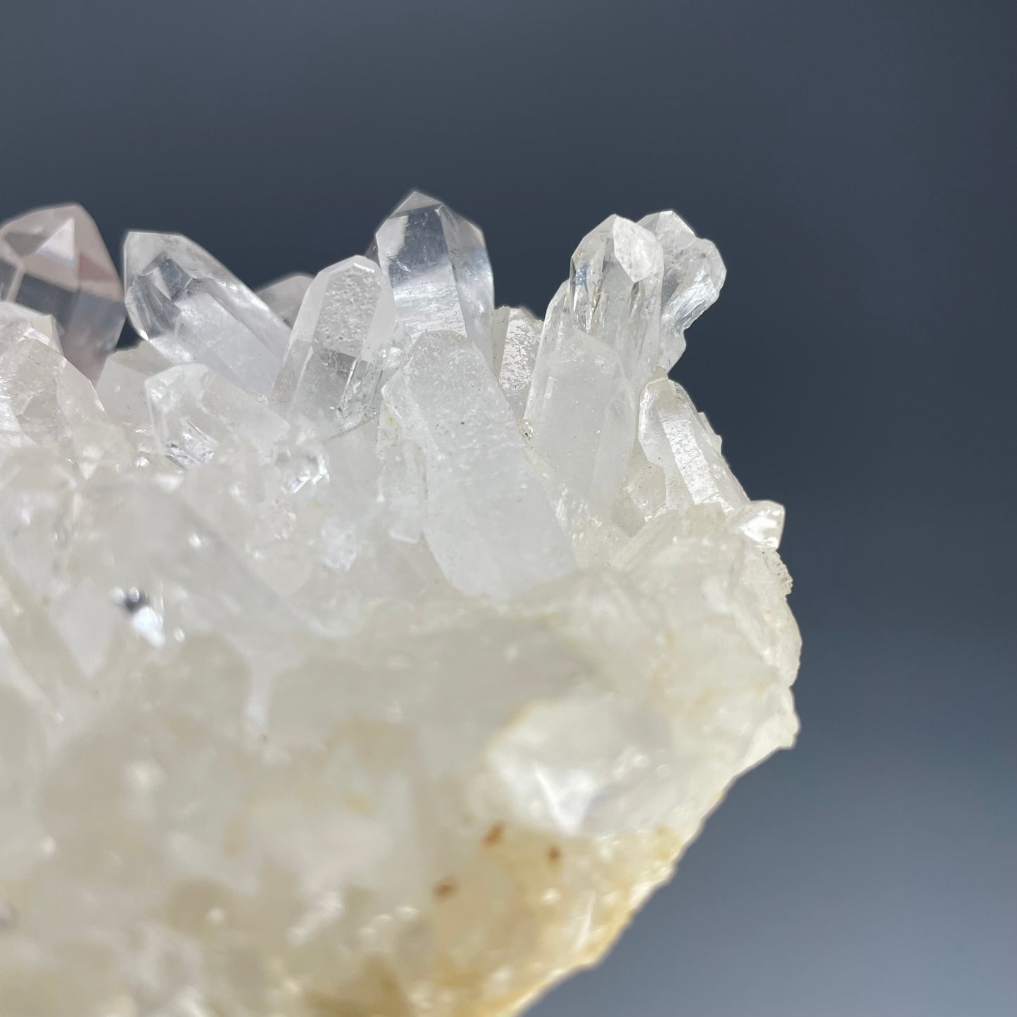 A natural Clear Quartz cluster with multiple crystal points, reflecting light beautifully against a neutral background.