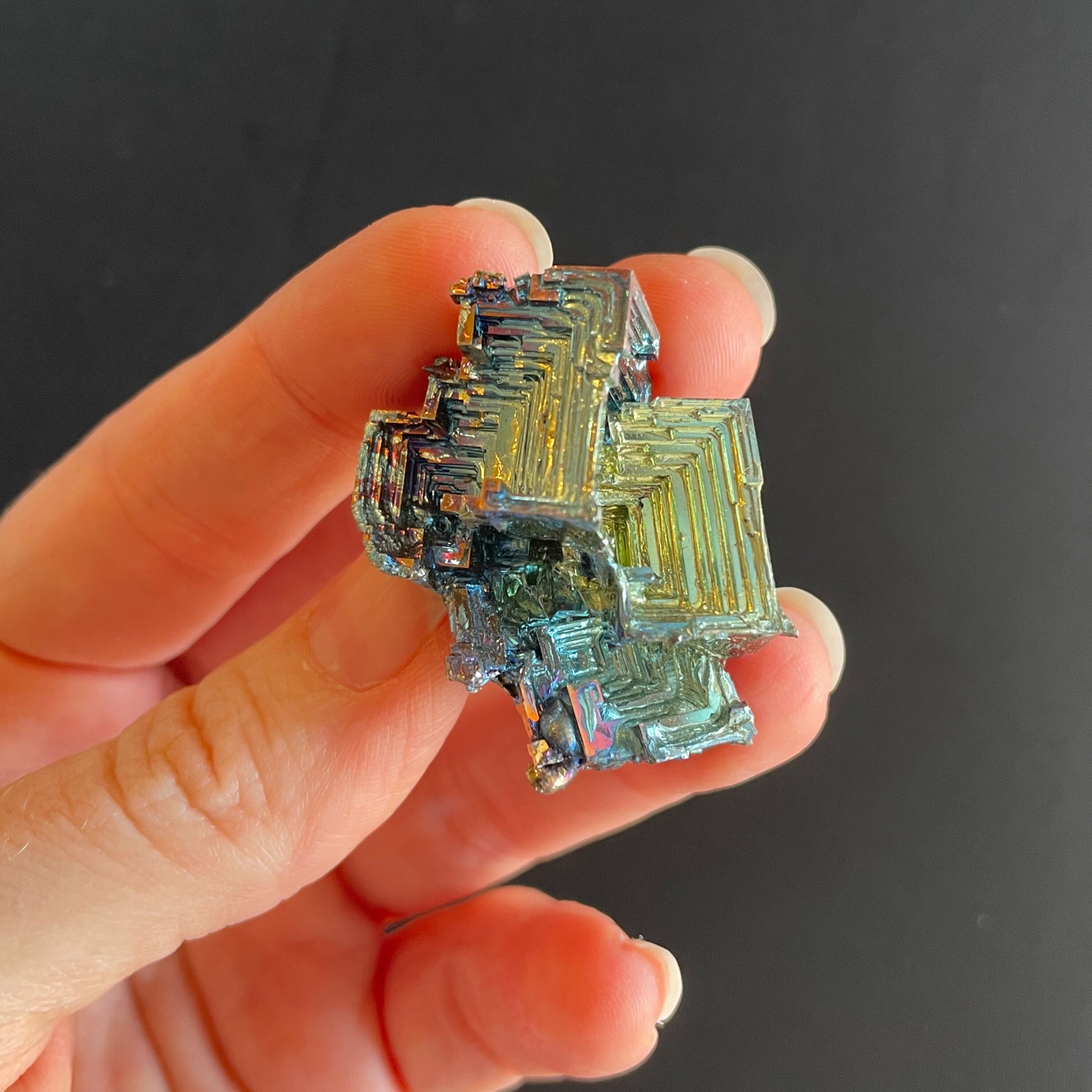 Assorted mini bismuth specimens, ranging from 2 mm to 3 mm in size, showcasing vibrant iridescent colors and intricate crystalline formations on a black background.