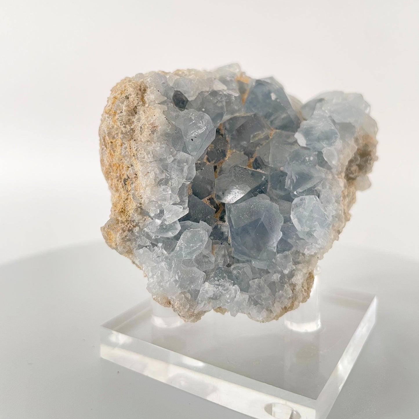 A close-up image of a sparkling celestite cluster, featuring various light blue crystals arranged in a natural formation. The crystals shimmer in the light, creating a mesmerizing and ethereal display.