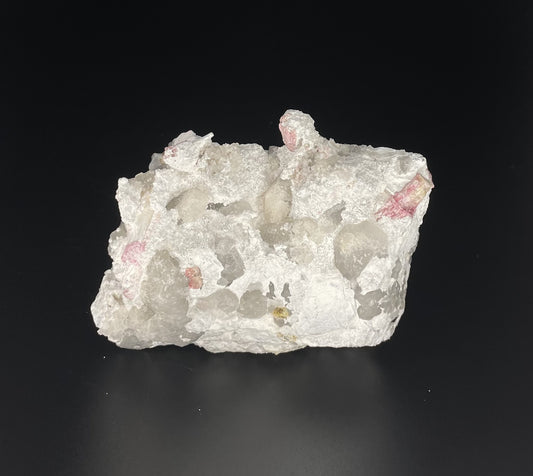  A close-up image of a mineral specimen featuring creamy Orthoclase crystals intergrown with clear quartz and dark tourmaline, showcasing a striking blend of textures and colors.