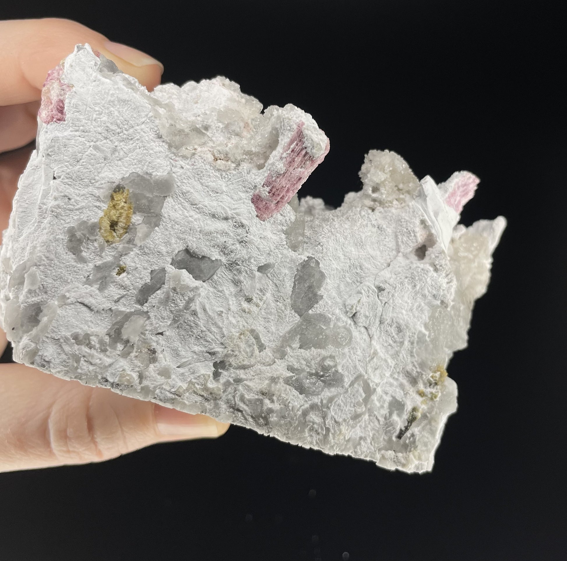  A close-up image of a mineral specimen featuring creamy Orthoclase crystals intergrown with clear quartz and dark tourmaline, showcasing a striking blend of textures and colors.