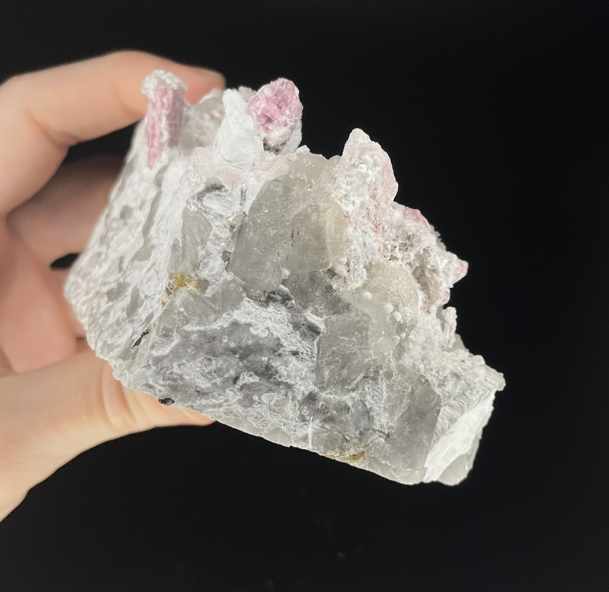  A close-up image of a mineral specimen featuring creamy Orthoclase crystals intergrown with clear quartz and dark tourmaline, showcasing a striking blend of textures and colors.