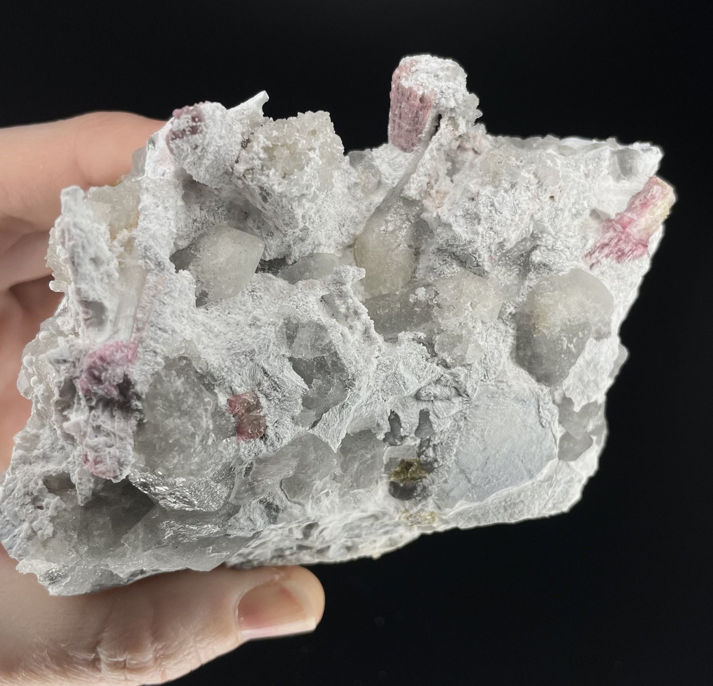  A close-up image of a mineral specimen featuring creamy Orthoclase crystals intergrown with clear quartz and dark tourmaline, showcasing a striking blend of textures and colors.