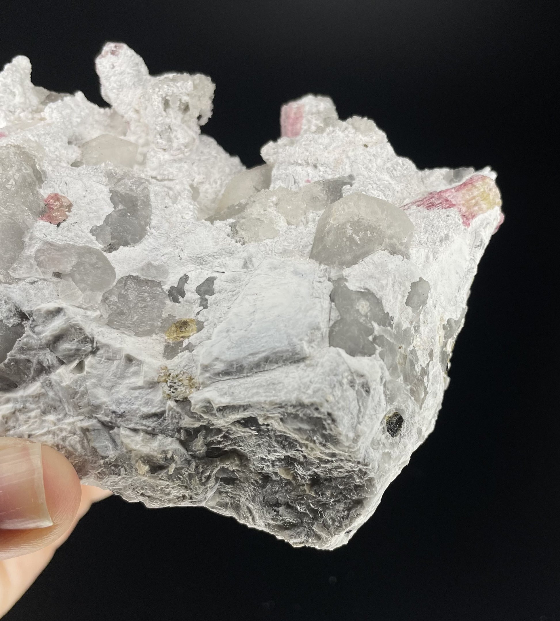  A close-up image of a mineral specimen featuring creamy Orthoclase crystals intergrown with clear quartz and dark tourmaline, showcasing a striking blend of textures and colors.