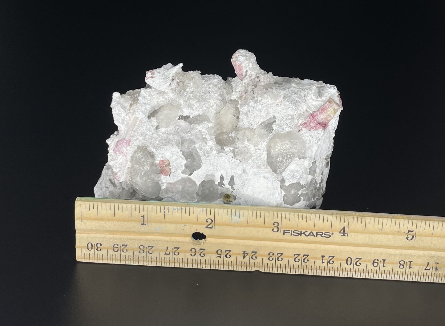  A close-up image of a mineral specimen featuring creamy Orthoclase crystals intergrown with clear quartz and dark tourmaline, showcasing a striking blend of textures and colors.