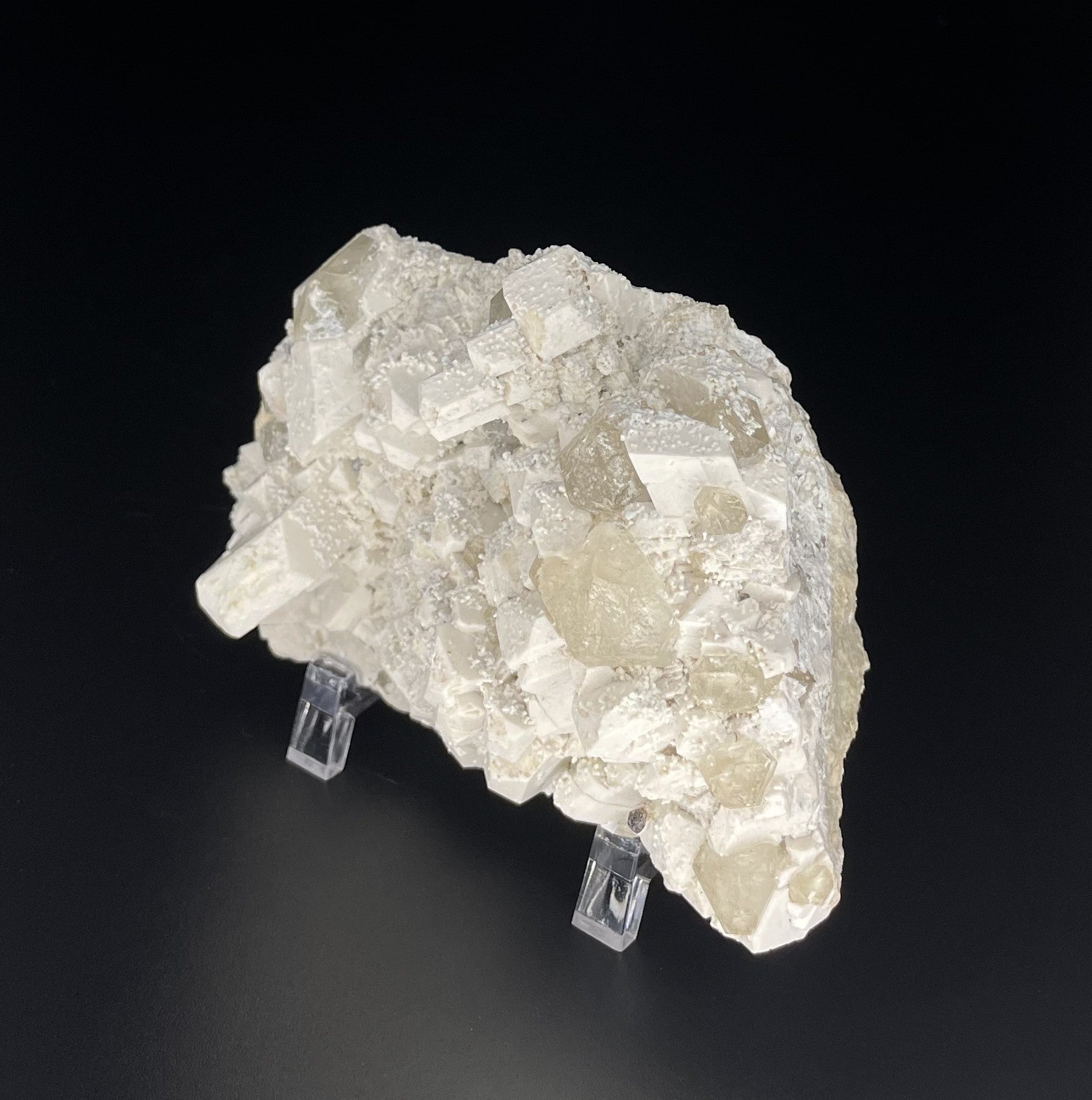  A close-up image of a mineral specimen featuring creamy Orthoclase crystals intergrown with clear quartz and dark tourmaline, showcasing a striking blend of textures and colors.