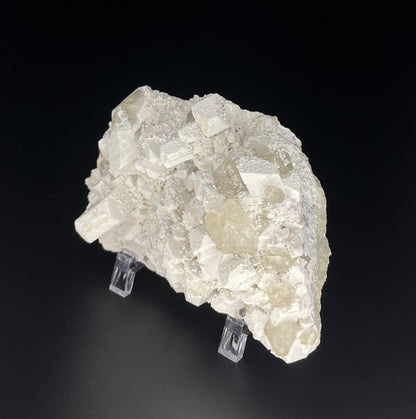  A close-up image of a mineral specimen featuring creamy Orthoclase crystals intergrown with clear quartz and dark tourmaline, showcasing a striking blend of textures and colors.