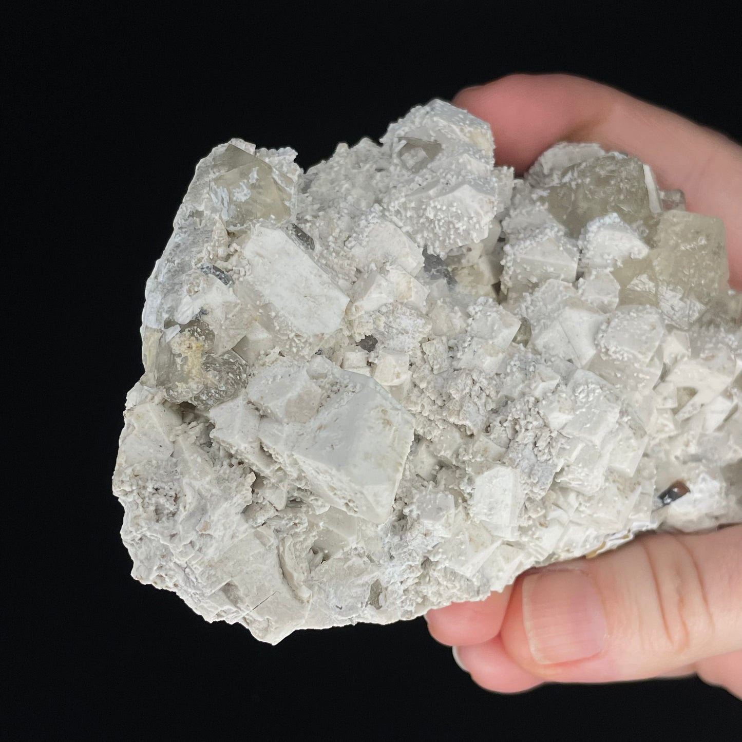  A close-up image of a mineral specimen featuring creamy Orthoclase crystals intergrown with clear quartz and dark tourmaline, showcasing a striking blend of textures and colors.