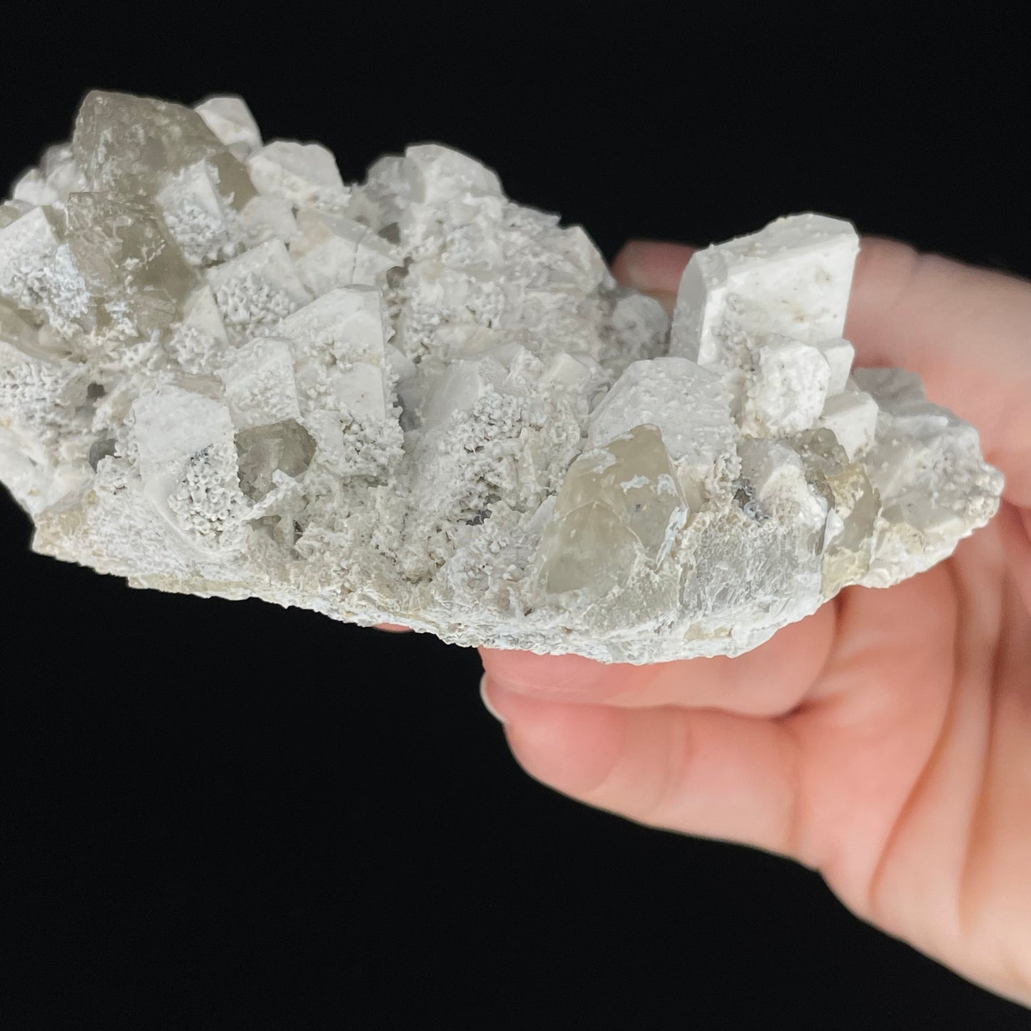  A close-up image of a mineral specimen featuring creamy Orthoclase crystals intergrown with clear quartz and dark tourmaline, showcasing a striking blend of textures and colors.