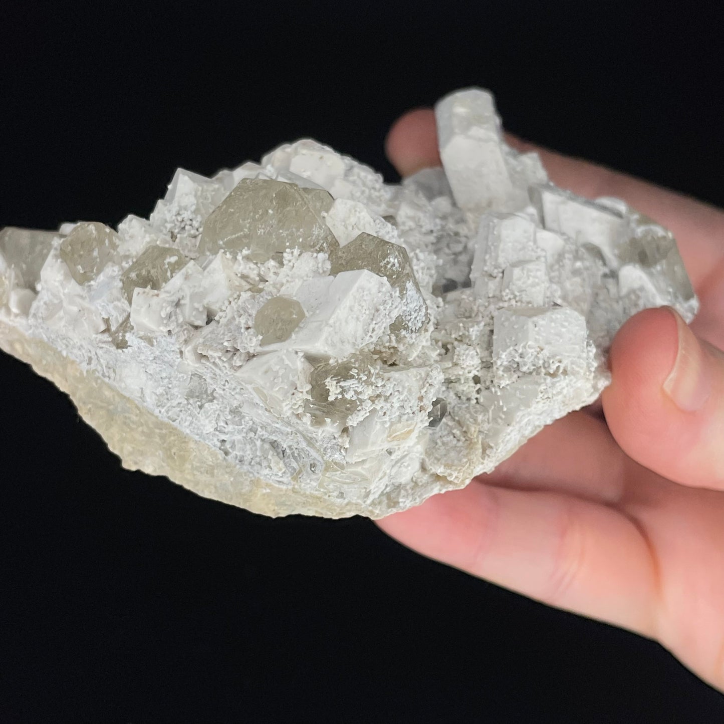  A close-up image of a mineral specimen featuring creamy Orthoclase crystals intergrown with clear quartz and dark tourmaline, showcasing a striking blend of textures and colors.