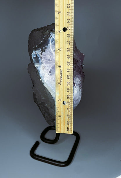 A Brazilian amethyst cluster with purple hues and large crystals on a black metal stand.