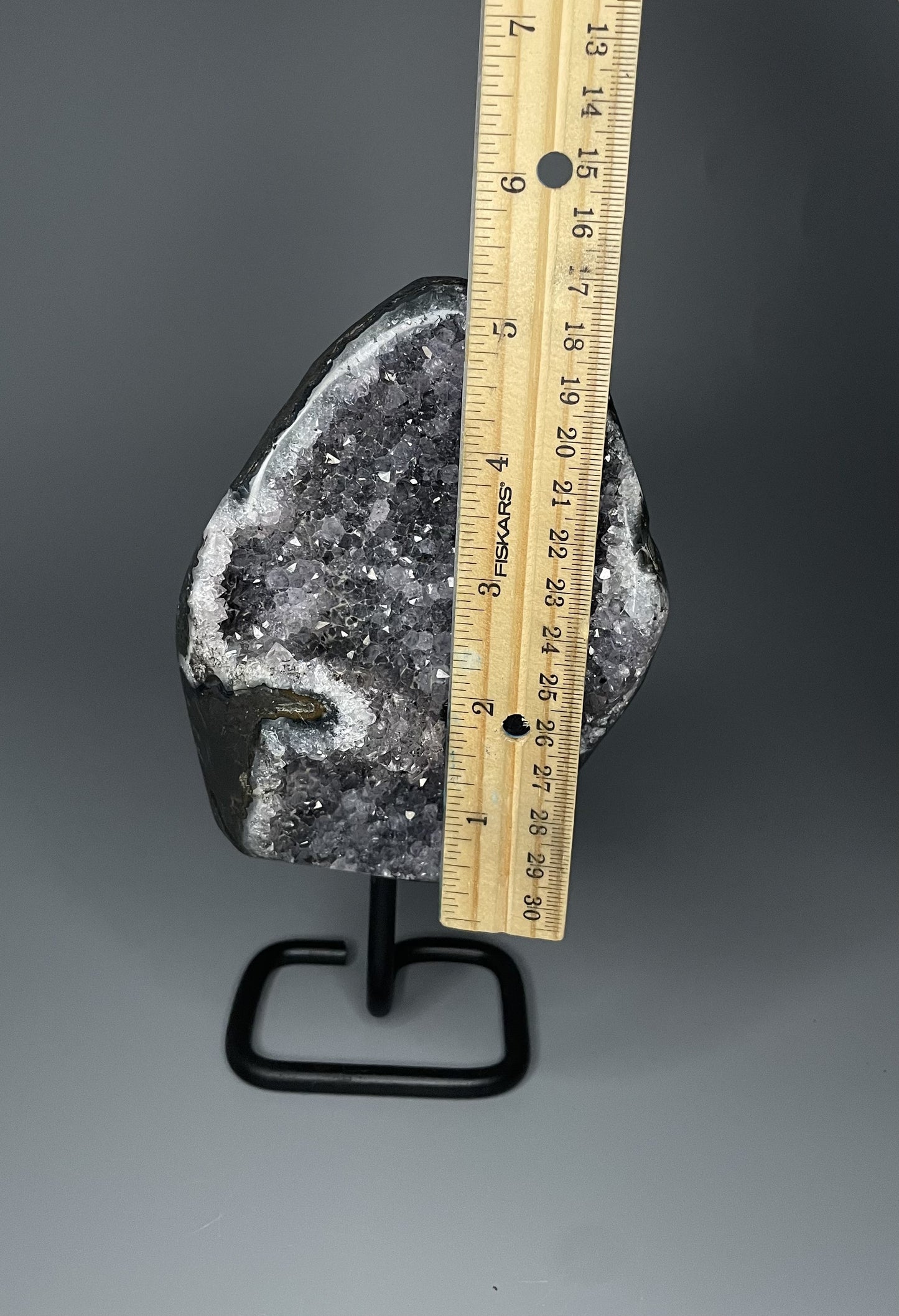 A Brazilian amethyst cluster with micro crystallization crystals on a black metal stand.