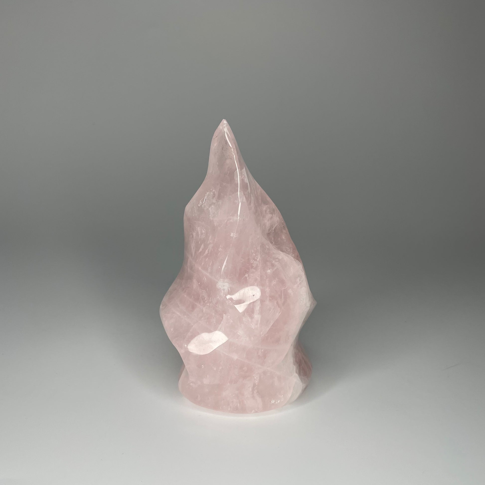 A 5-inch Rose Quartz Flame Carving with soft pink hues and a smooth, polished finish, shaped like a flickering flame, symbolizing love and transformation.