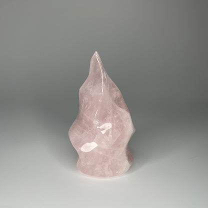 A 5-inch Rose Quartz Flame Carving with soft pink hues and a smooth, polished finish, shaped like a flickering flame, symbolizing love and transformation.