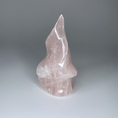 A 5-inch Rose Quartz Flame Carving with soft pink hues and a smooth, polished finish, shaped like a flickering flame, symbolizing love and transformation.