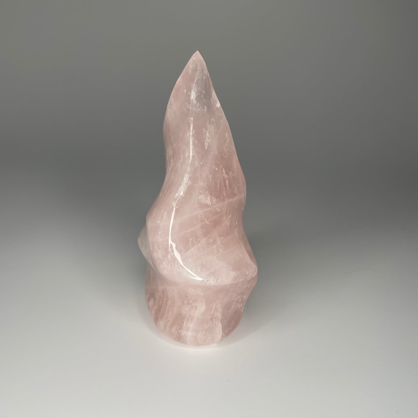 A 5-inch Rose Quartz Flame Carving with soft pink hues and a smooth, polished finish, shaped like a flickering flame, symbolizing love and transformation.