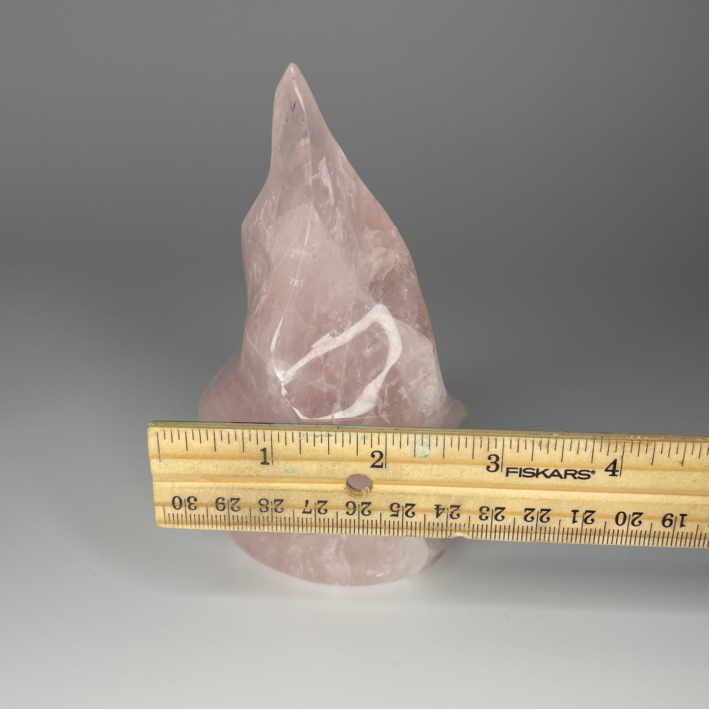 A 5-inch Rose Quartz Flame Carving with soft pink hues and a smooth, polished finish, shaped like a flickering flame, symbolizing love and transformation.