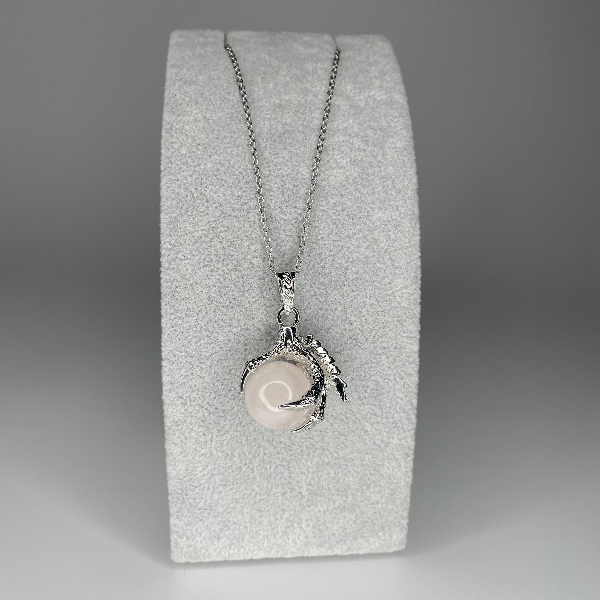 A 3 cm pendant featuring a detailed claw holding a tiny mineral sphere, available in various stones, hanging from a stainless steel chain.