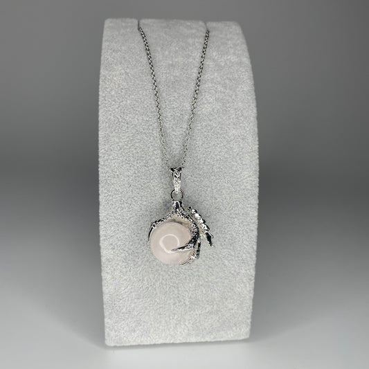 A 3 cm pendant featuring a detailed claw holding a tiny mineral sphere, available in various stones, hanging from a stainless steel chain.