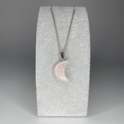 A 3 cm crescent moon pendant carved from various minerals hanging from a stainless steel chain