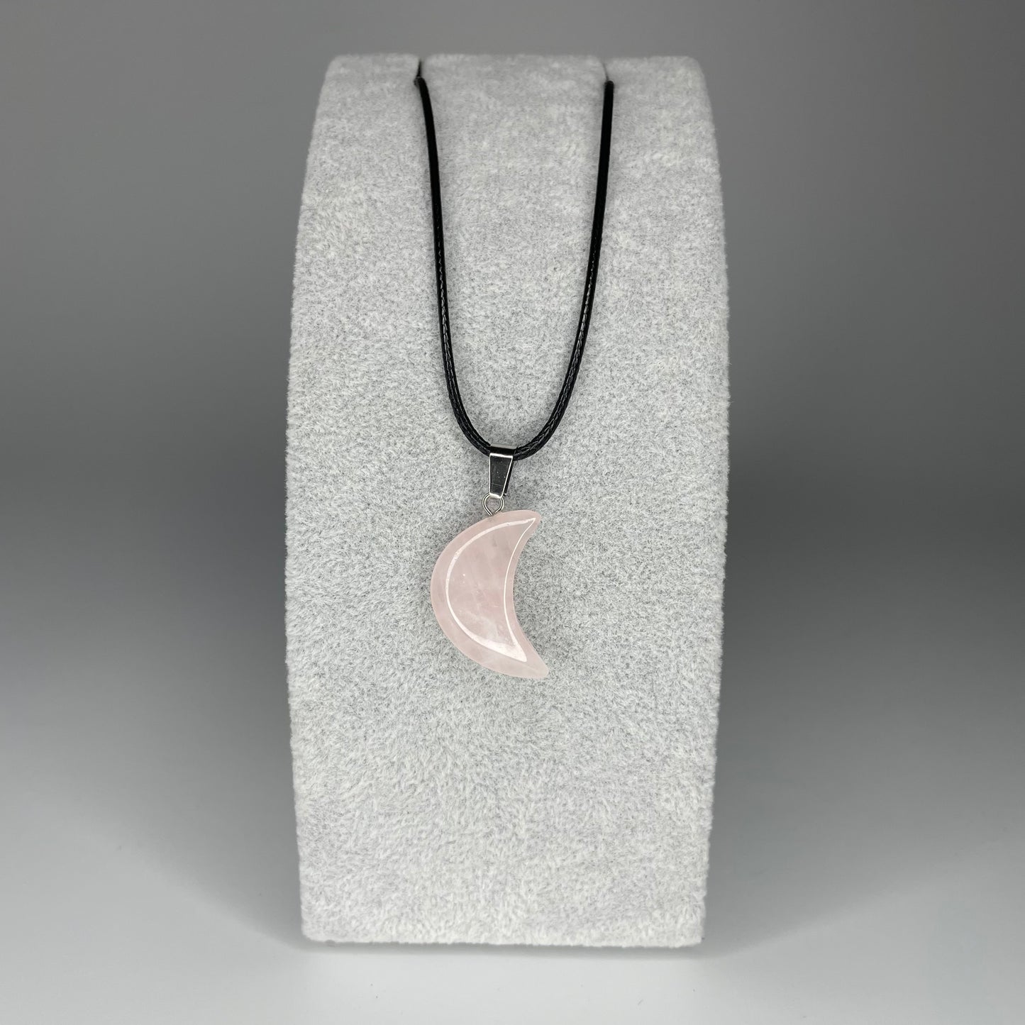 A 3 cm crescent moon pendant carved from various minerals hanging from a black nylon necklace.