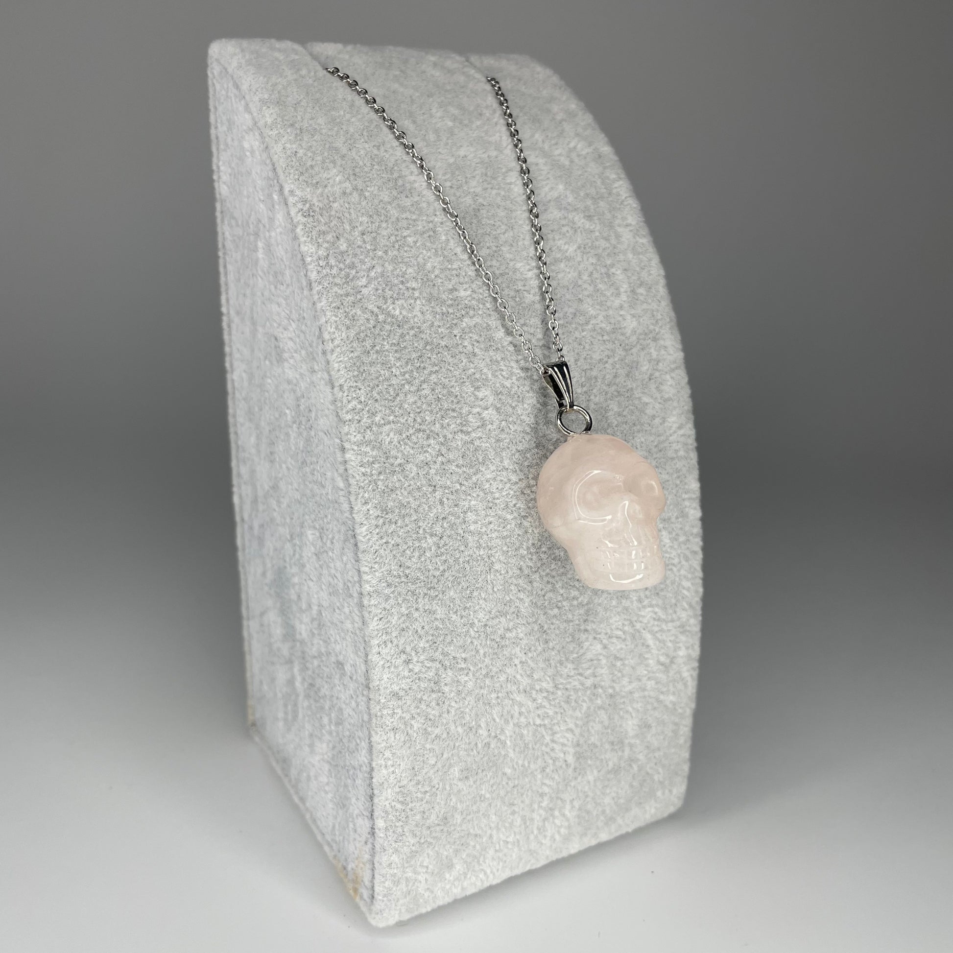 A 3 cm skull pendant carved from various minerals, symbolizing wisdom and transformation, with a stainless steel chain.